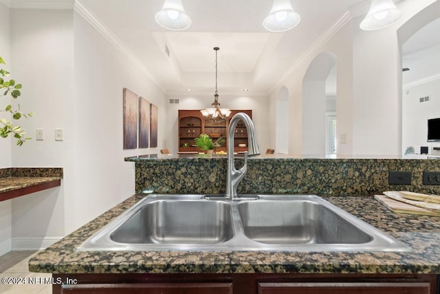 room details featuring hanging light fixtures, crown molding, sink, and a chandelier