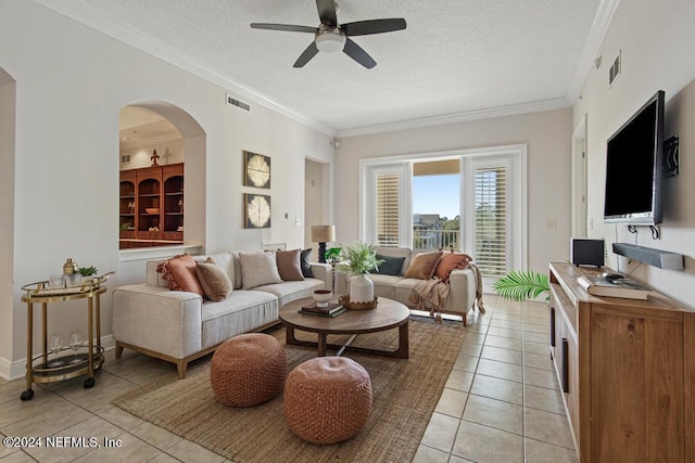 living room with ceiling fan, light tile patterned floors, a textured ceiling, and ornamental molding