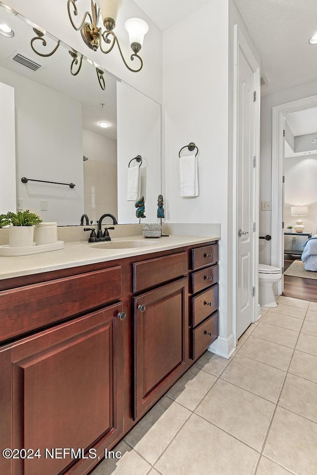 bathroom featuring toilet, tile patterned flooring, vanity, and an inviting chandelier