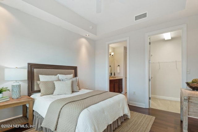 bedroom with connected bathroom, a spacious closet, ceiling fan, dark hardwood / wood-style floors, and a closet