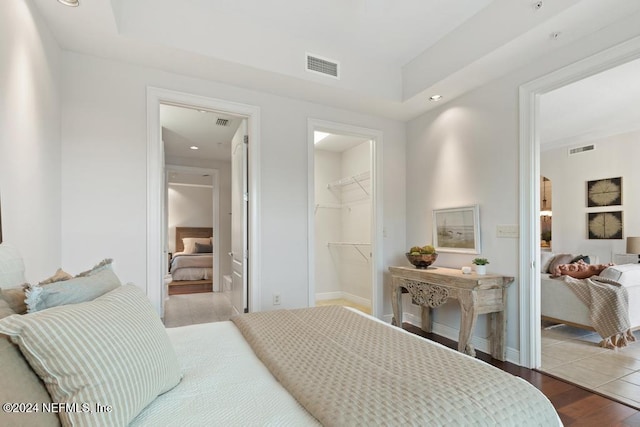 bedroom with a walk in closet, a closet, and light hardwood / wood-style flooring