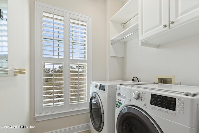 clothes washing area with washer and dryer, a healthy amount of sunlight, and cabinets