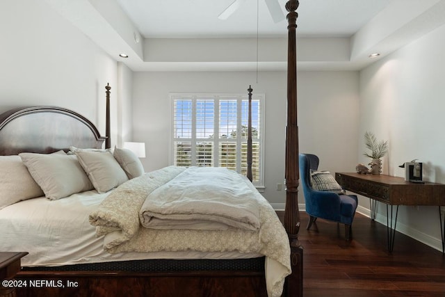 bedroom featuring a raised ceiling, ceiling fan, and dark hardwood / wood-style flooring