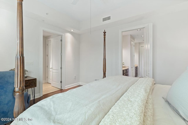 bedroom with ensuite bathroom, light hardwood / wood-style flooring, and ceiling fan