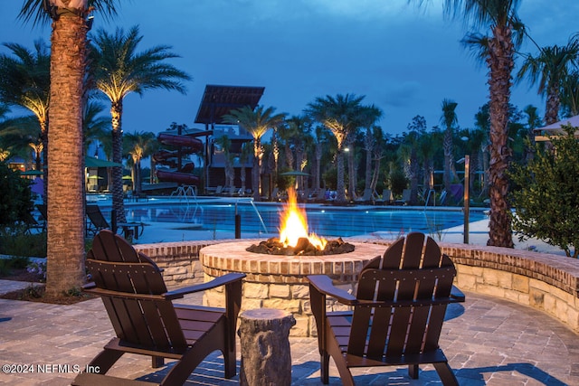 view of pool with a patio area, pool water feature, and an outdoor fire pit