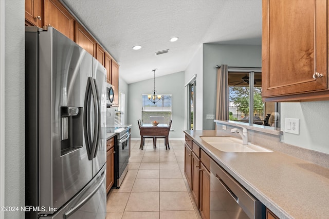 kitchen featuring stainless steel appliances, vaulted ceiling, sink, pendant lighting, and an inviting chandelier