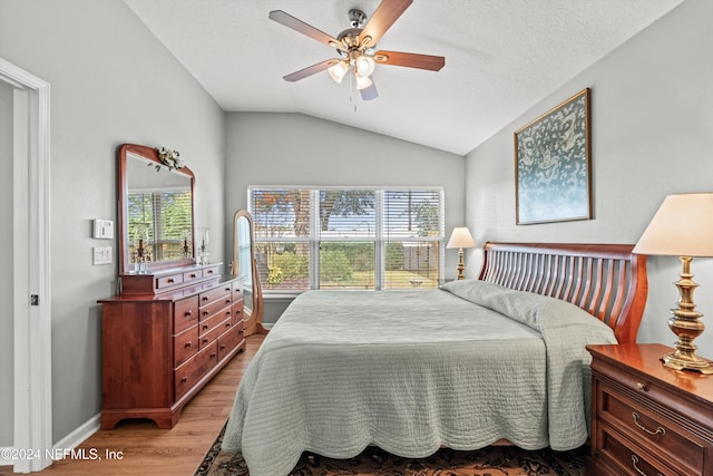 bedroom featuring light wood-type flooring, vaulted ceiling, multiple windows, and ceiling fan