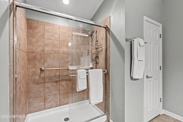 bathroom with a shower with door and tile patterned flooring