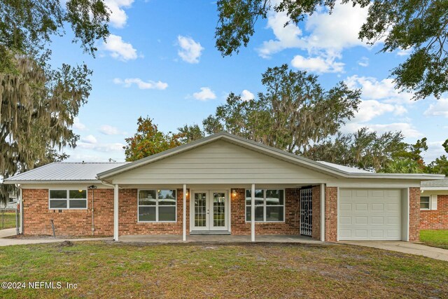 ranch-style house with a front lawn, a garage, and french doors