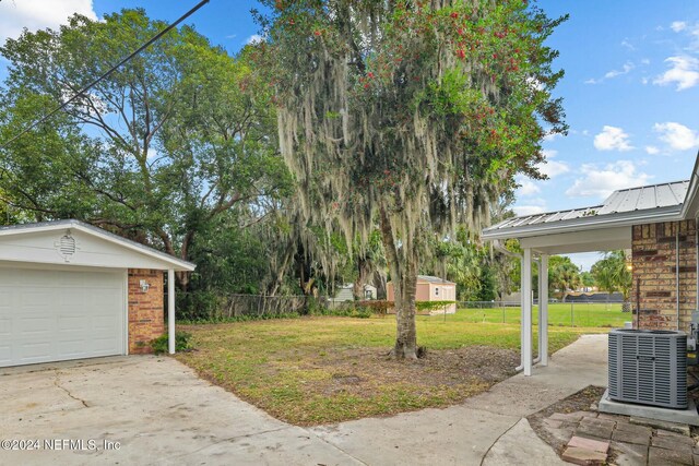 view of yard featuring central AC unit, a garage, and an outbuilding