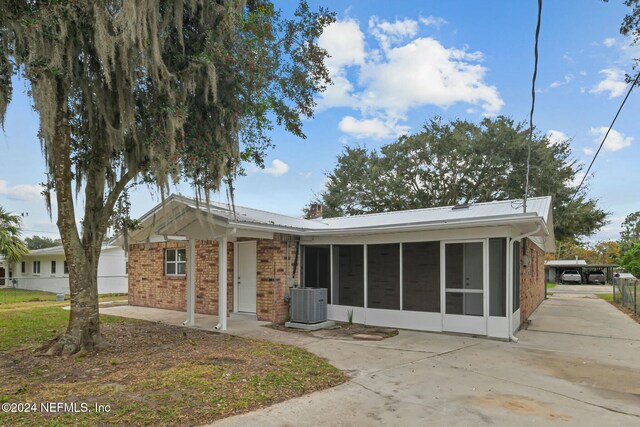 ranch-style home with central AC, a sunroom, and a patio area