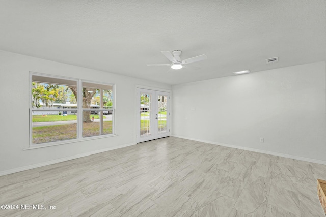 empty room with ceiling fan, a textured ceiling, and french doors