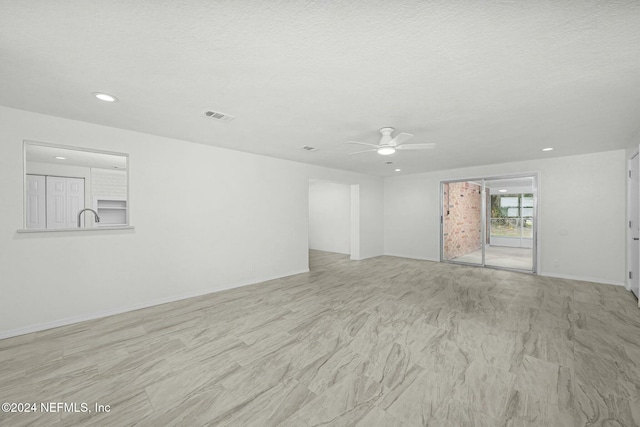 empty room with ceiling fan and a textured ceiling