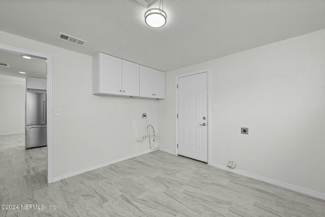 clothes washing area with hookup for an electric dryer, gas dryer hookup, and a textured ceiling