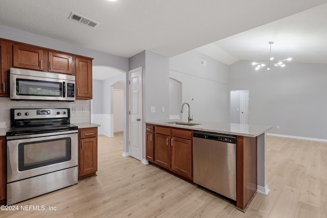 kitchen with lofted ceiling, sink, light hardwood / wood-style flooring, stainless steel appliances, and a chandelier