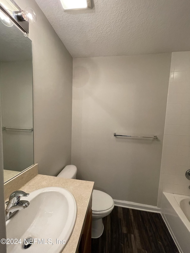 full bathroom featuring shower / bathing tub combination, wood-type flooring, a textured ceiling, toilet, and vanity