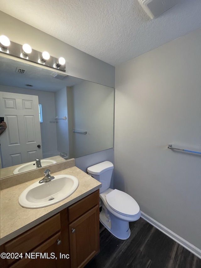 bathroom with hardwood / wood-style floors, vanity, a textured ceiling, and toilet