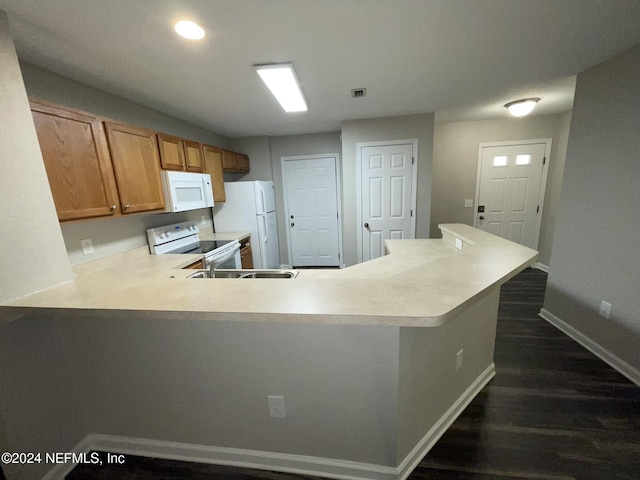 kitchen with kitchen peninsula, white appliances, and dark wood-type flooring