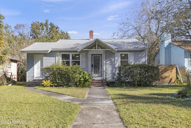 bungalow-style house featuring a chimney, a front yard, and fence