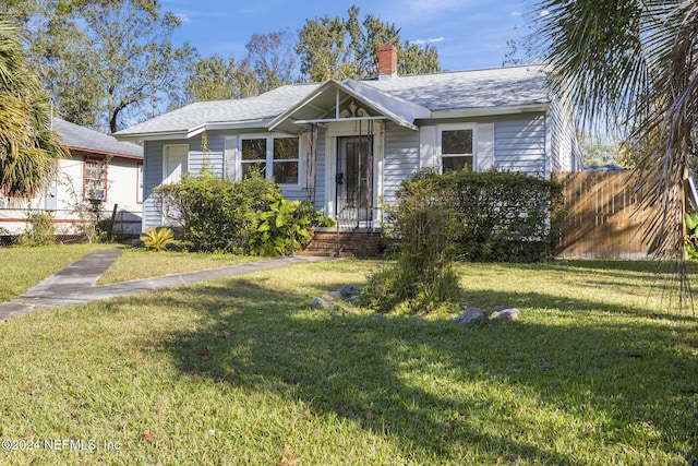 bungalow-style house featuring a chimney, fence, and a front lawn