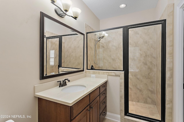 bathroom with vanity, a shower with shower door, and a textured ceiling