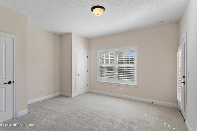 unfurnished bedroom with a textured ceiling and light carpet