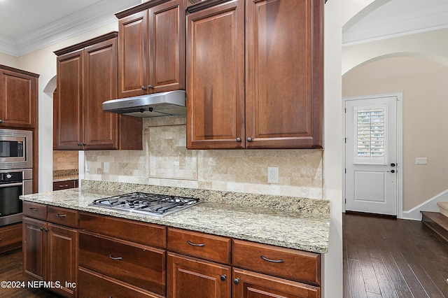 kitchen featuring light stone countertops, dark hardwood / wood-style flooring, tasteful backsplash, stainless steel appliances, and crown molding