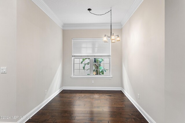 empty room with a notable chandelier, ornamental molding, and dark wood-type flooring