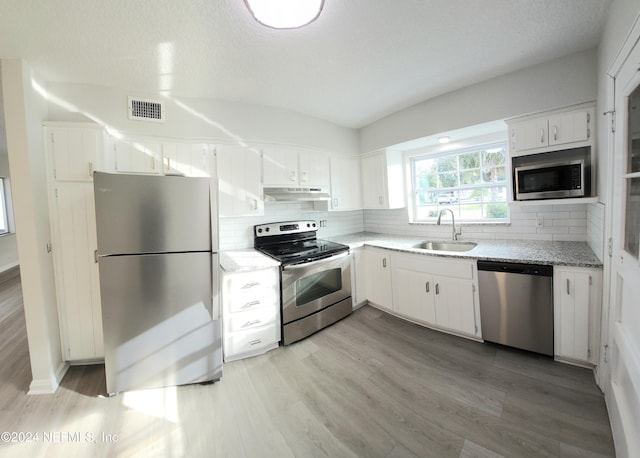 kitchen featuring light wood-type flooring, tasteful backsplash, stainless steel appliances, sink, and white cabinets