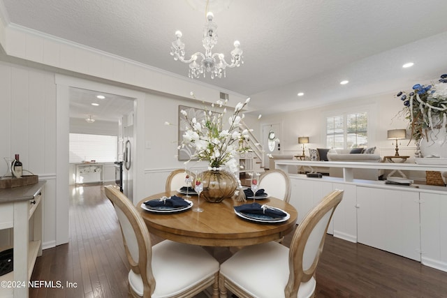 dining room with a textured ceiling, a notable chandelier, dark hardwood / wood-style floors, and ornamental molding