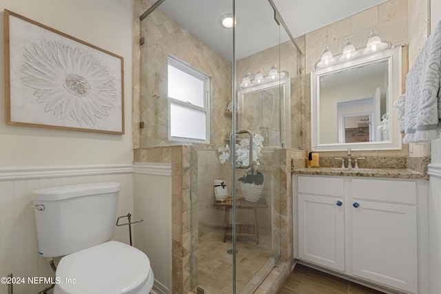 bathroom featuring a textured ceiling, vanity, toilet, and a shower with door