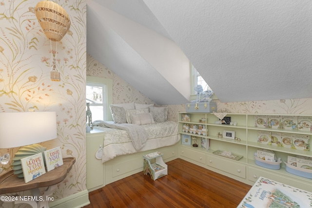 bedroom featuring a textured ceiling, vaulted ceiling, and hardwood / wood-style flooring