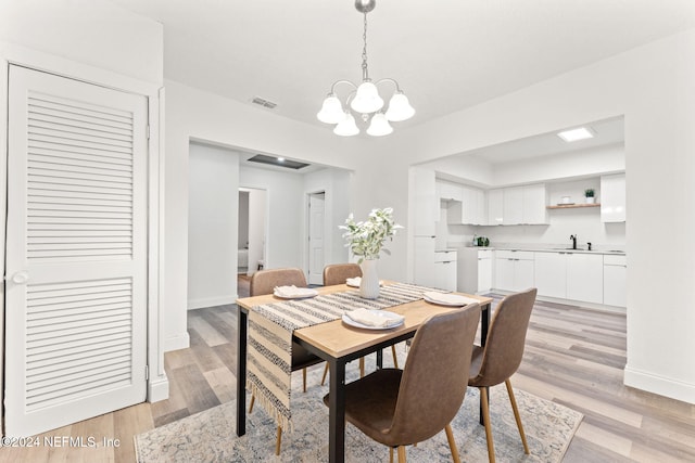 dining room with a notable chandelier, light hardwood / wood-style floors, and sink