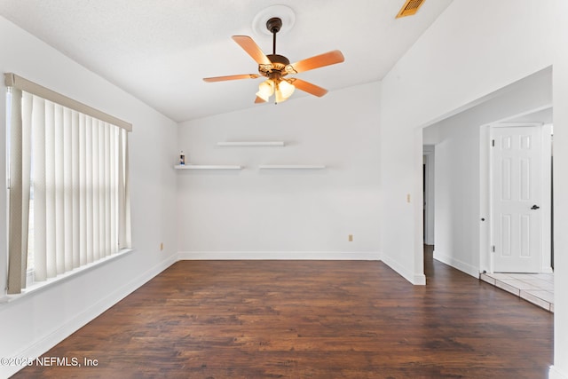 spare room featuring dark hardwood / wood-style floors, vaulted ceiling, and ceiling fan