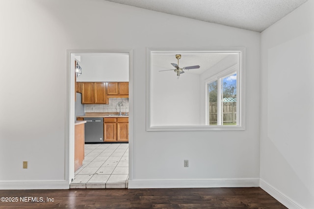 kitchen featuring stainless steel dishwasher, vaulted ceiling, ceiling fan, sink, and backsplash