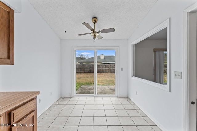 unfurnished dining area featuring a textured ceiling, light tile patterned floors, and ceiling fan