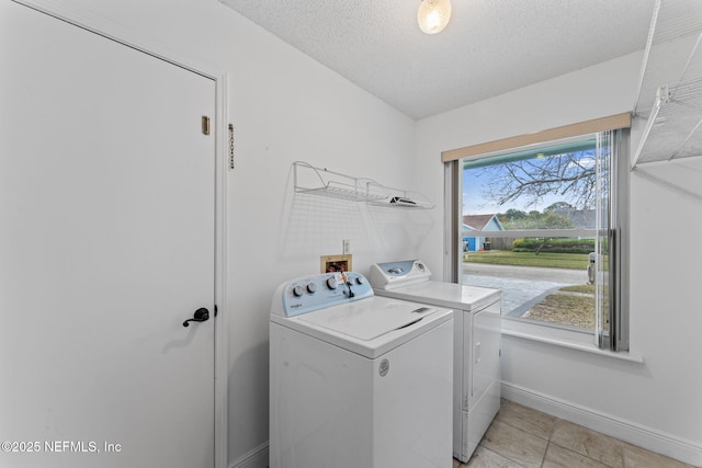 laundry area featuring light tile patterned flooring, a textured ceiling, and washer and dryer