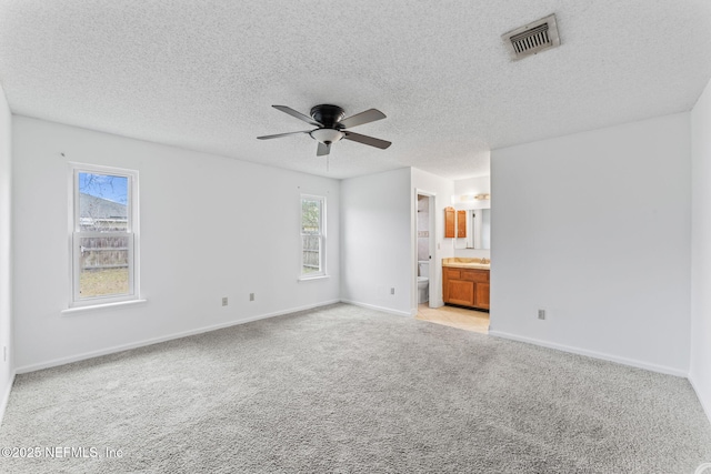 carpeted empty room featuring ceiling fan, a healthy amount of sunlight, and a textured ceiling