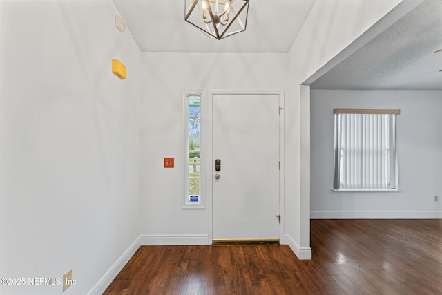 foyer entrance featuring dark hardwood / wood-style floors, a notable chandelier, and a healthy amount of sunlight