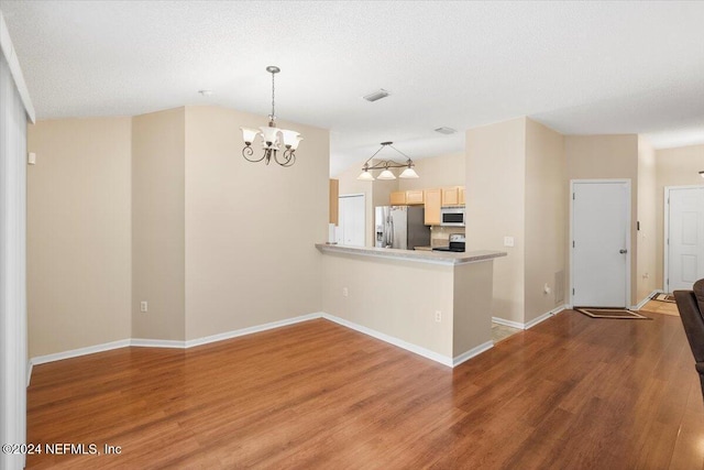 kitchen with hanging light fixtures, hardwood / wood-style flooring, light brown cabinets, and appliances with stainless steel finishes