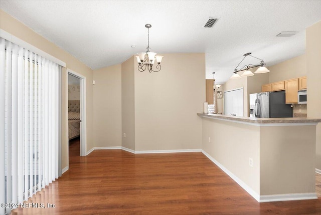 kitchen with decorative light fixtures, stainless steel fridge, kitchen peninsula, and wood-type flooring