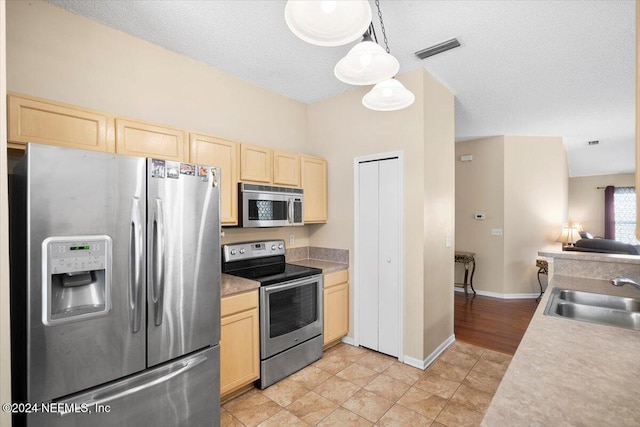 kitchen with sink, a textured ceiling, light brown cabinets, pendant lighting, and stainless steel appliances