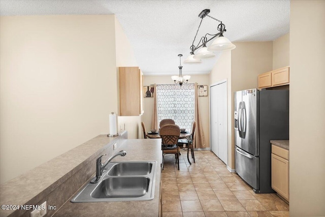 kitchen featuring pendant lighting, sink, stainless steel fridge, an inviting chandelier, and a textured ceiling