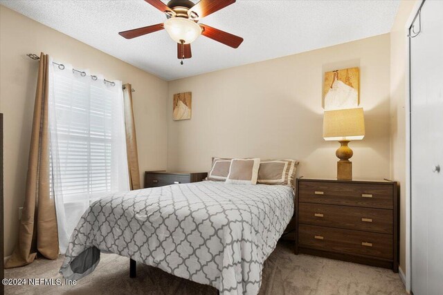 bedroom featuring light carpet, ceiling fan, and a textured ceiling