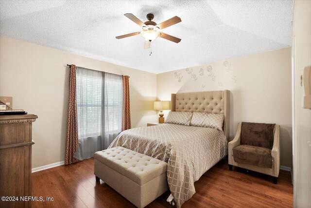 bedroom featuring ceiling fan, dark hardwood / wood-style floors, and a textured ceiling