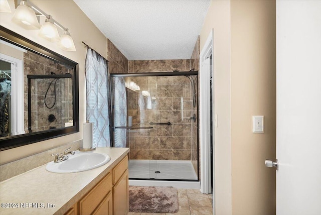 bathroom with vanity, a shower with door, and a textured ceiling