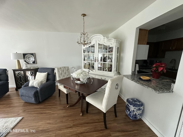 dining area featuring sink, dark wood-type flooring, and a notable chandelier