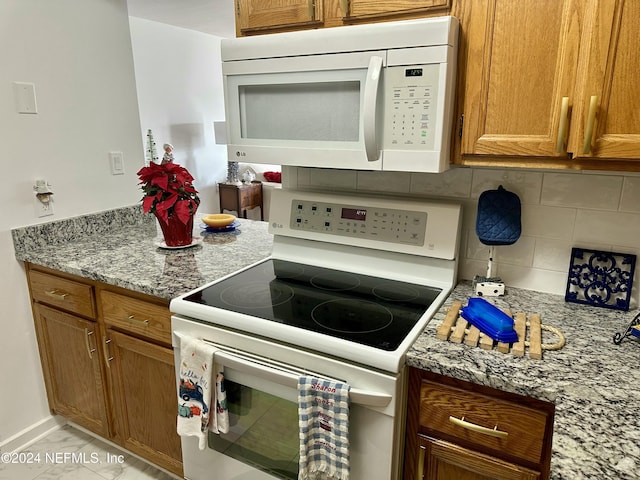 kitchen featuring decorative backsplash, white appliances, and light stone countertops