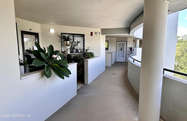 hall featuring a textured ceiling, plenty of natural light, and washing machine and clothes dryer