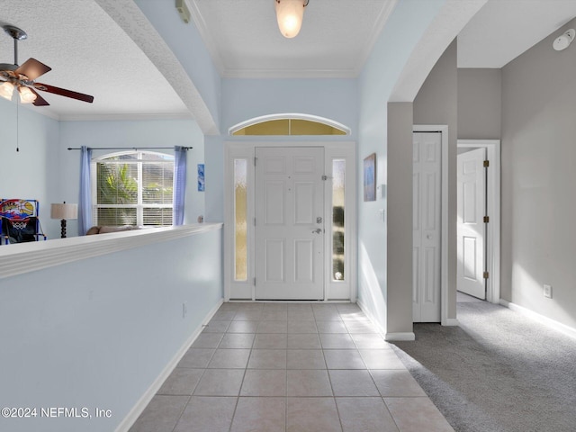 tiled entrance foyer featuring a textured ceiling, ceiling fan, and crown molding